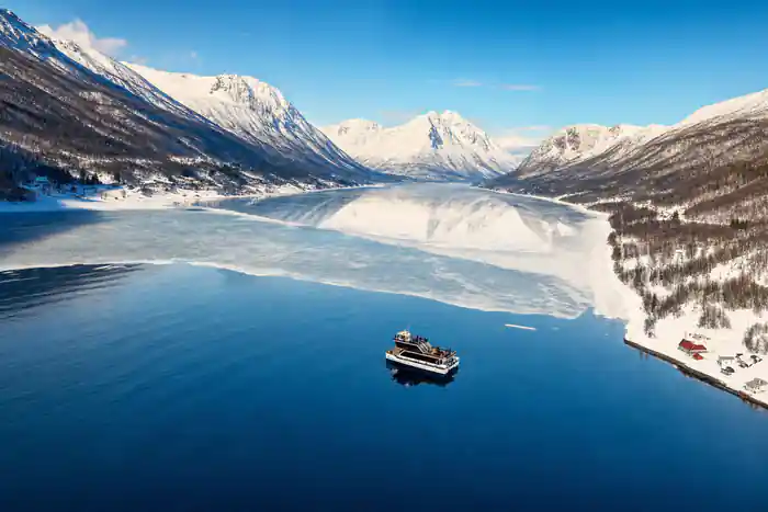 Boat on frozen lake surrounded by snow-covered mountains