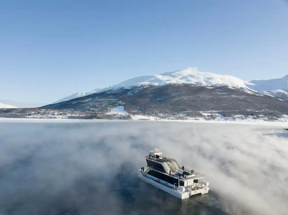 Boat on misty frozen lake with snow mountain in background