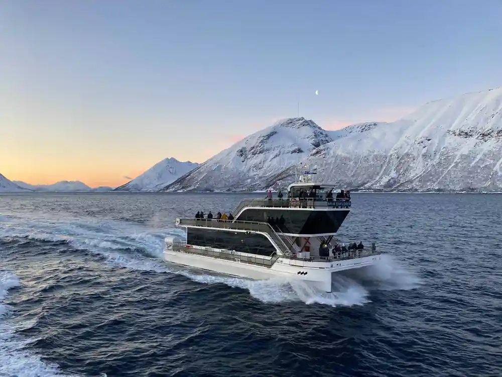 Boat traveling through snowy fjord with snow-capped mountains