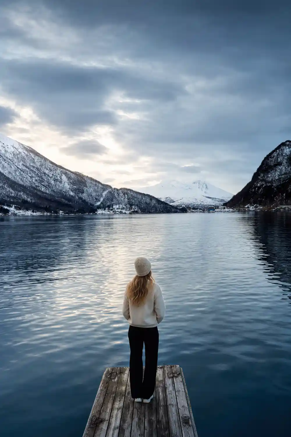 Lake surrounded by snow-covered mountains and forested slopes