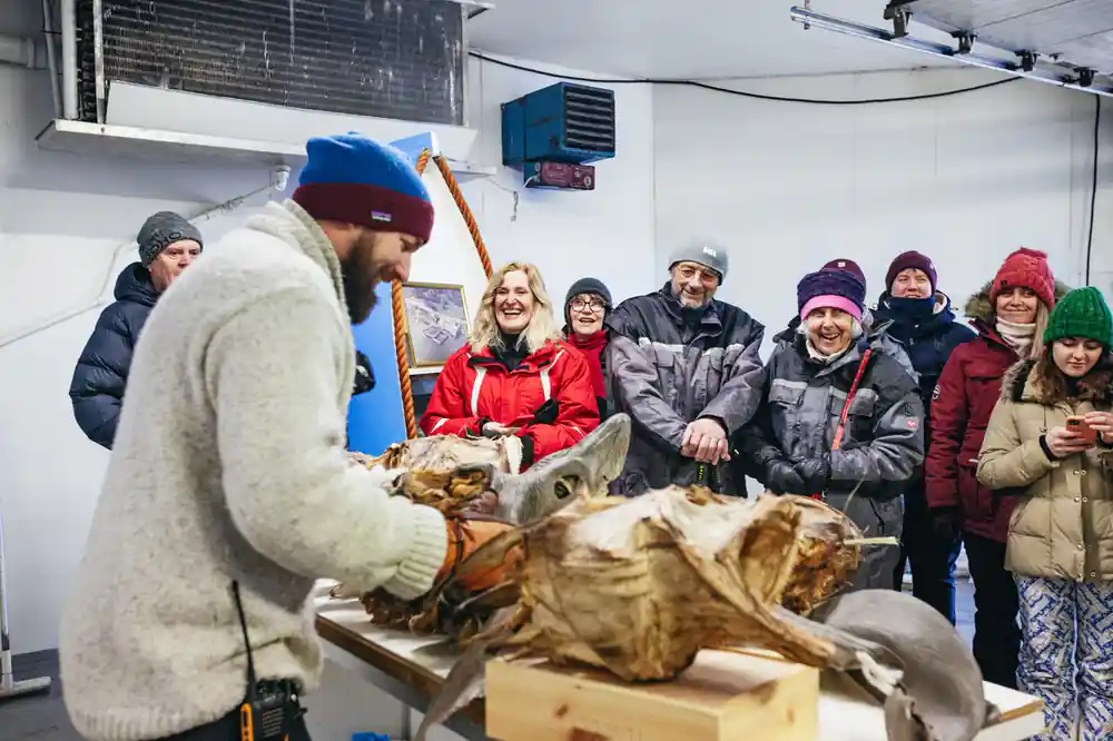 Man demonstrating dried fish to group of winter-dressed people