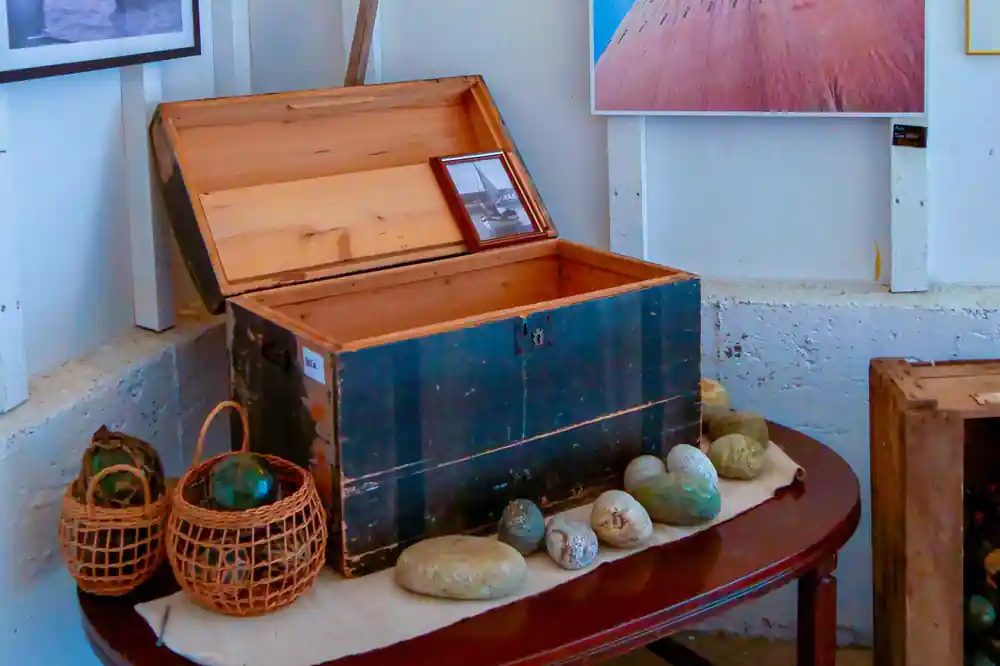 Museum display of vintage trunk with fishing baskets and stones