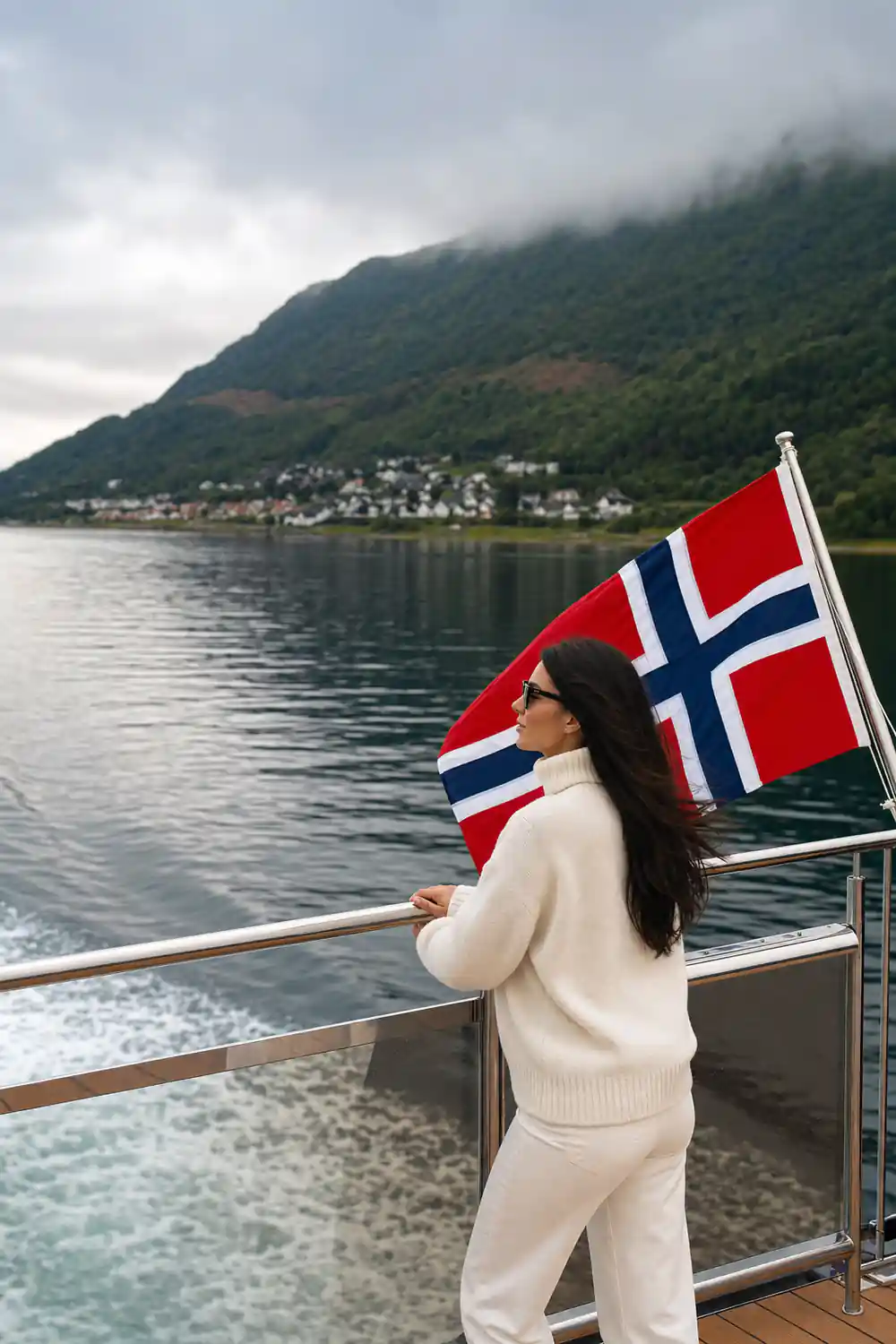 Norwegian flag on boat railing overlooking fjord valley