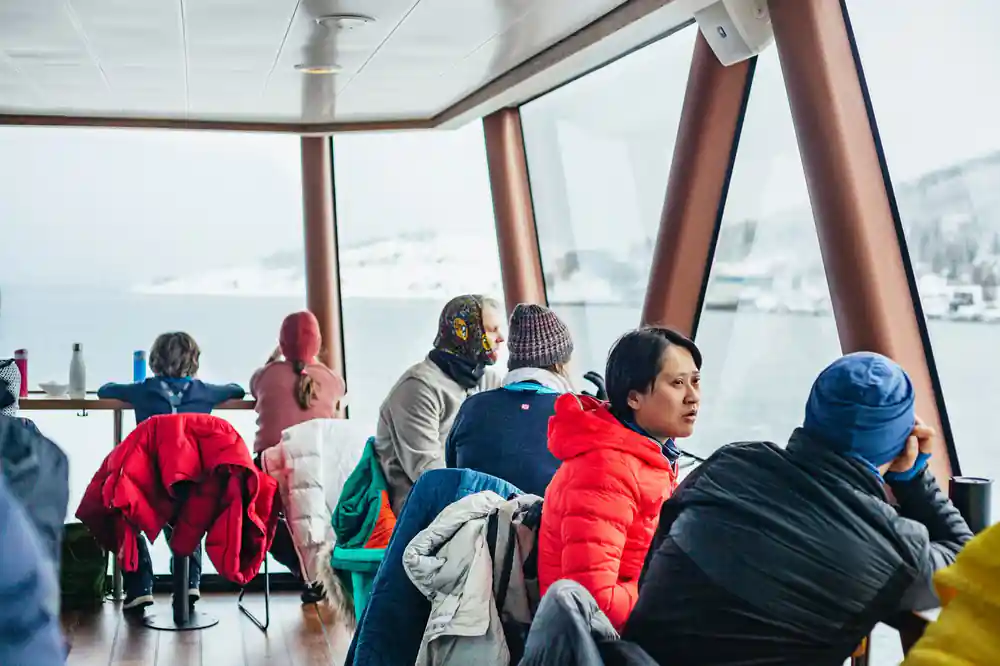 Passengers inside heated boat cabin viewing snowy landscape