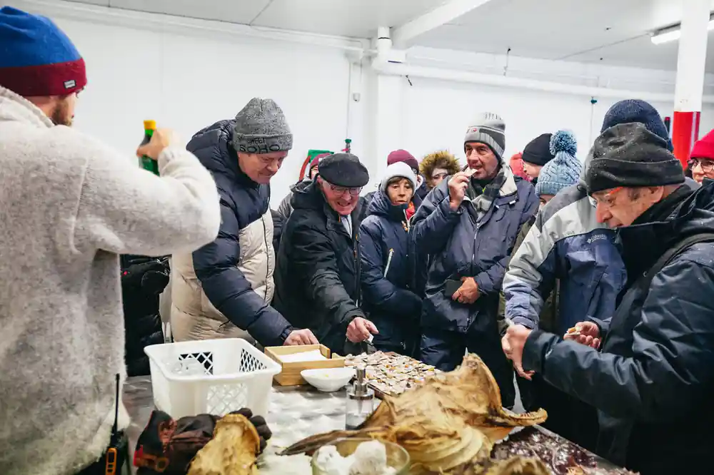 People gathered indoors examining dried fish and food products