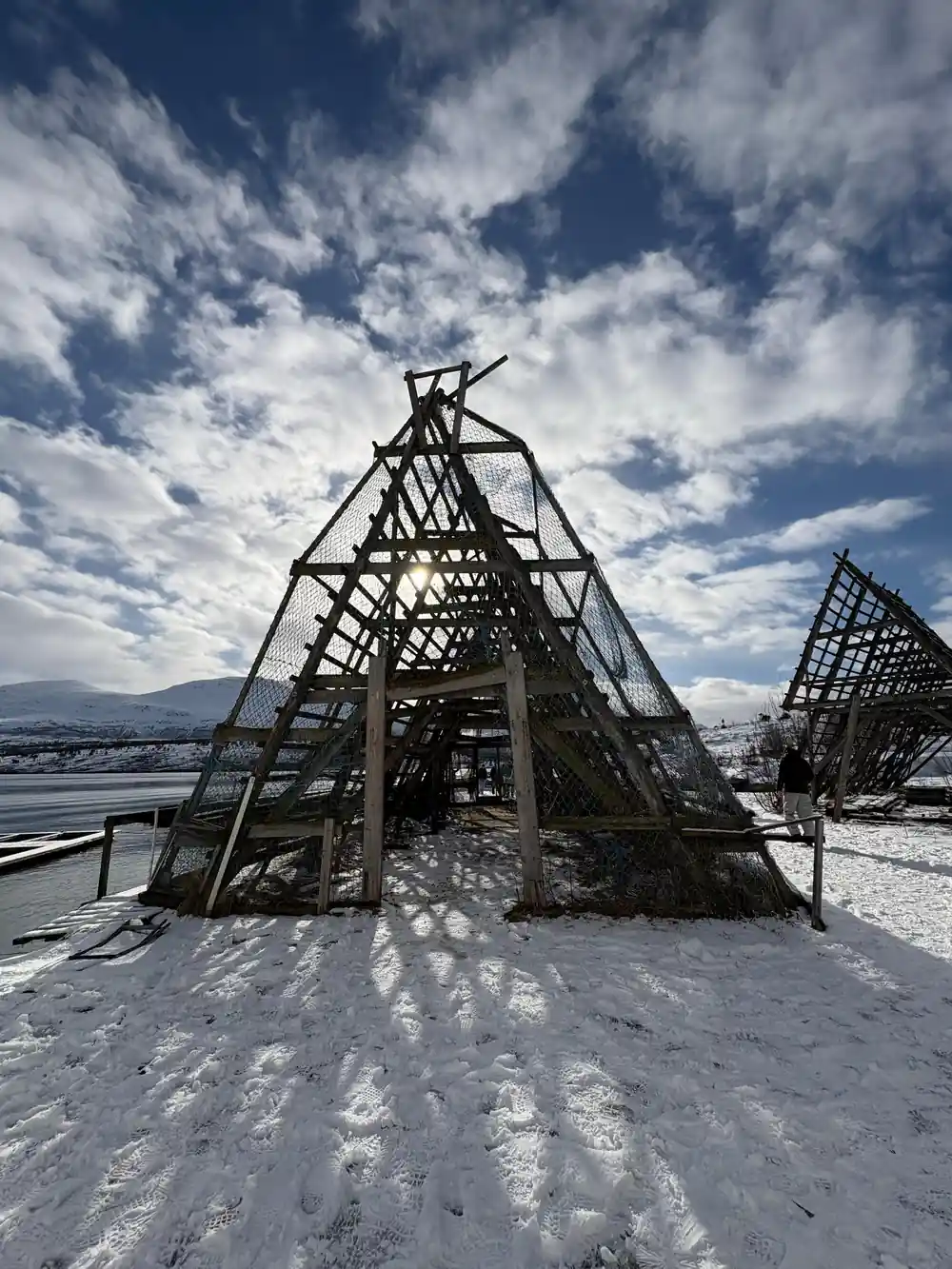 Skeletal wooden boat frame against sky with mountain backdrop