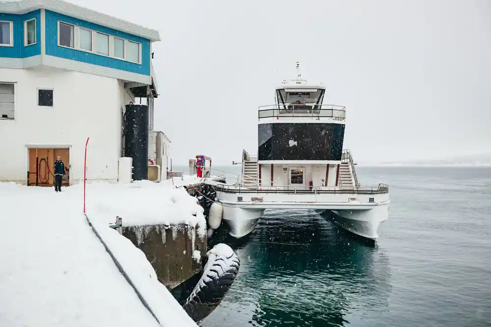 Small white boat docked at snowy waterfront building