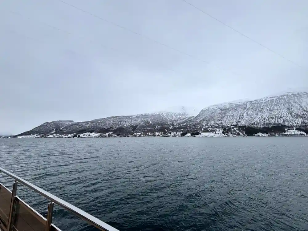 Snow-capped mountain range across water from boat