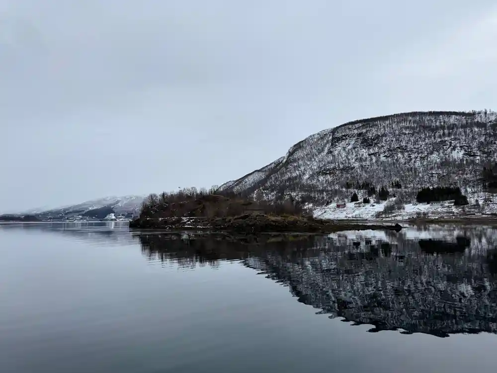 Snowy mountainside with village reflected in calm water