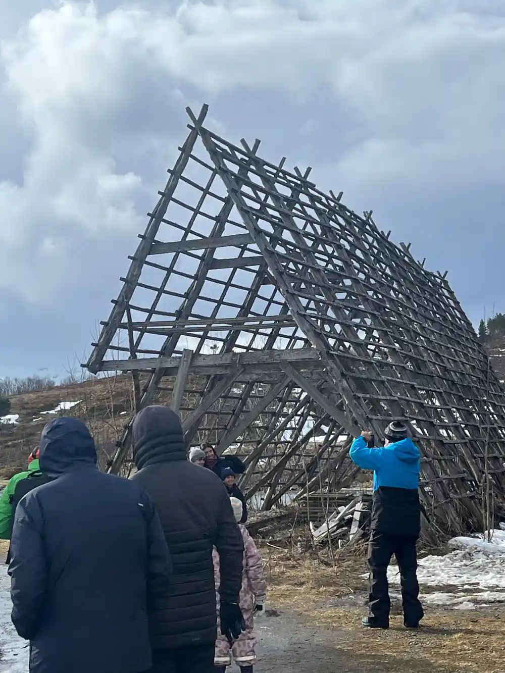 Wooden frame structure with visitors standing nearby on ground